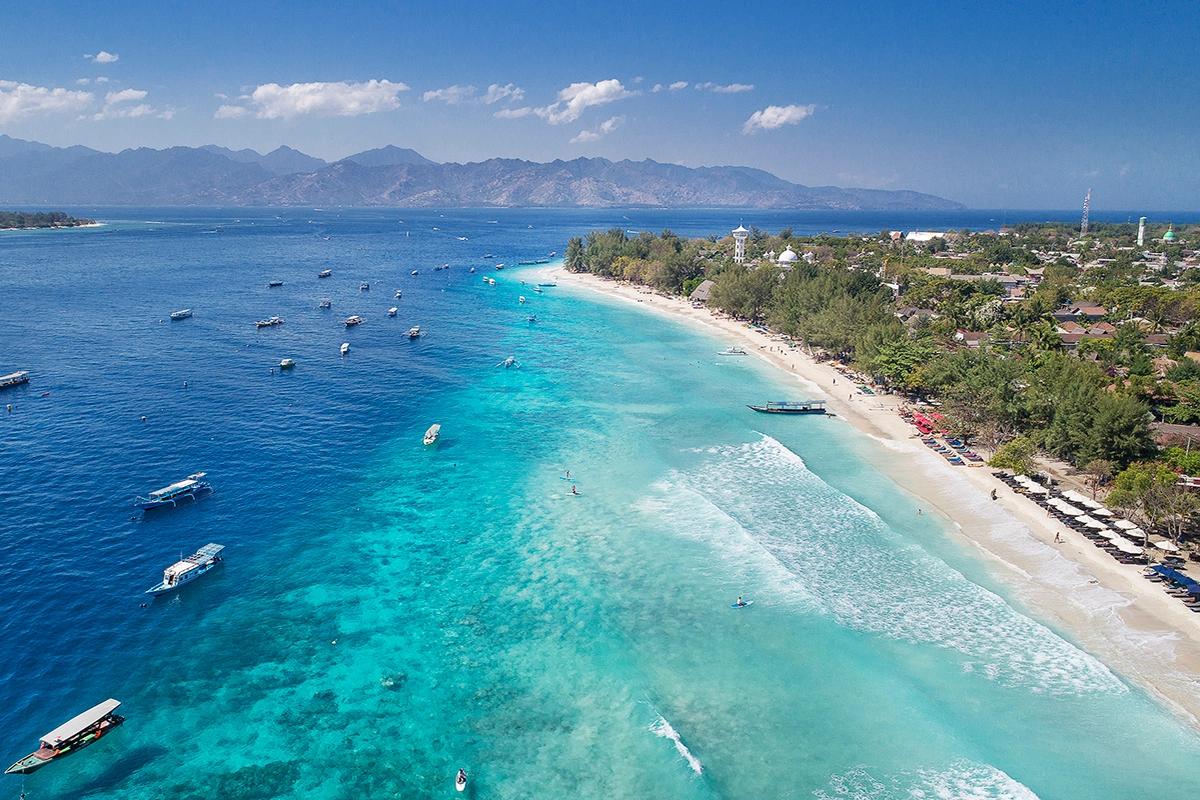 Boats anchored off the beaches of the Gili Islands with Lombok's mountains behind