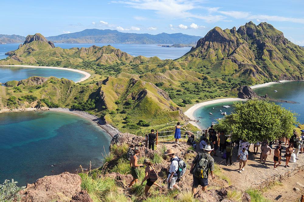 Hikers on the trail up Padar Island hill at golden hour